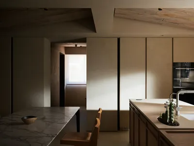 Modern kitchen with minimalist design, featuring a marble countertop and wooden furniture.