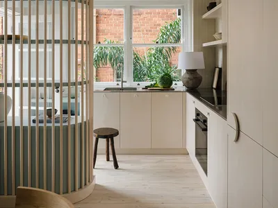 Modern kitchen featuring wooden cabinets, sleek countertops, and a large window overlooking greenery.