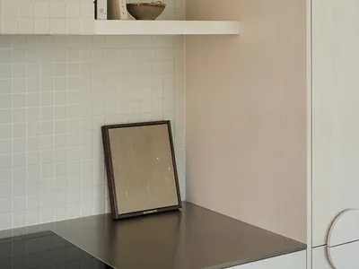 A modern kitchen with a wooden shelf and a tiled wall.