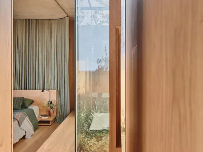 A minimalist bedroom featuring wooden furniture and green curtains.