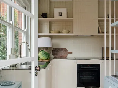 A minimalist residential kitchen with wood finishes and white cabinets.