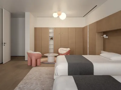 Modern minimalist bedroom with wooden walls and built-in cabinets, featuring a pink accent chair and table, and a comfortable
