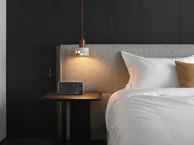 Modern minimalist bedroom featuring a fabric mattress against a dark wooden wall with a hanging pendant light and a nightstan