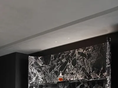 A modern industrial bar counter made of marble with black and white veins, featuring a sleek design with a single chair and a