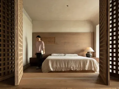 A serene, minimalist bedroom featuring wooden furniture and a neutral color palette.