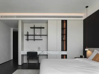 Modern bedroom featuring white marble floors and walls, minimalist design, and white bedding.