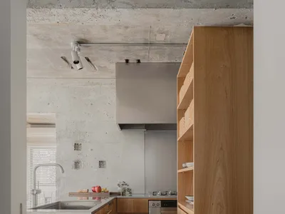 A modern kitchen with wooden cabinets and a concrete ceiling