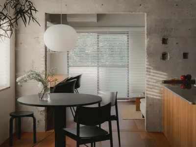 A modern minimalist kitchen with concrete walls and a round table.