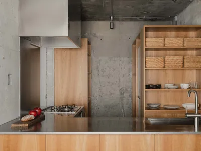 Modern minimalist residential kitchen with concrete hexagonal patterned backsplash, wooden cabinetry, and stainless steel app