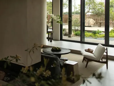 A minimalistic living room with concrete walls and a view of a garden.