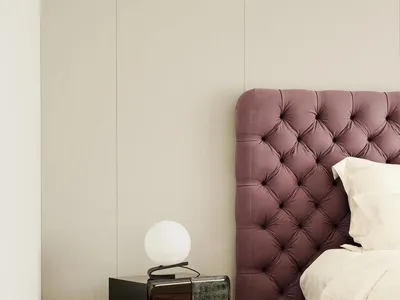 現代極簡臥室，配有紫色絎縫布面床頭板，以及一張俐落黑色邊桌，桌上擺放白色球形燈具