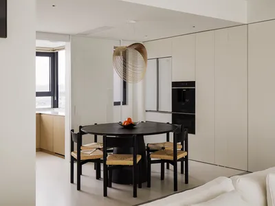 A modern kitchen with wooden furniture, a white countertop, and a black dining table.