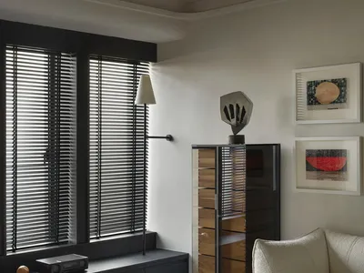 A minimalist bedroom featuring a white couch, black accents, and modern art on the walls.