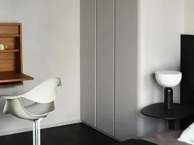 A minimalist bedroom featuring neutral-toned furniture and a contemporary interior design with integrated storage solutions.