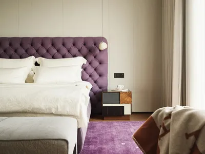 A modern bedroom with a purple upholstered bed and wooden furniture.