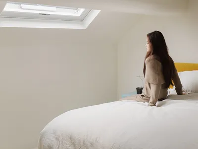 A minimalist bedroom with a white blanket and yellow bed