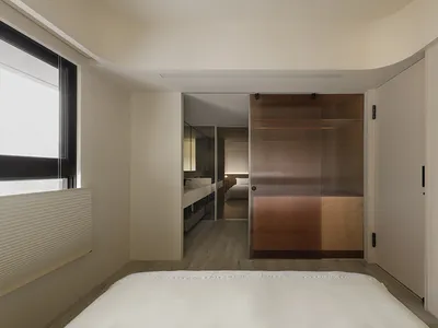 Modern minimalist bedroom featuring a wooden floor and furniture.