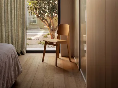 Modern minimalist bedroom with wooden furniture and a large window overlooking greenery.