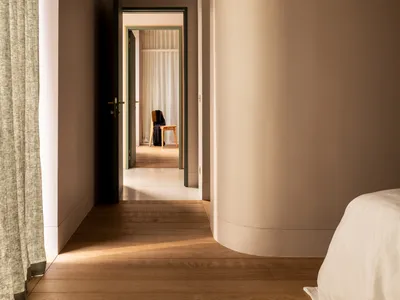 Modern minimalist bedroom with a wooden accent wall and natural light streaming through the window.