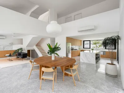 A minimalist kitchen with wooden furniture, marble countertops, and a terrazzo floor.