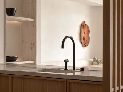 Modern kitchen featuring minimalist design, stone countertops, and wooden cabinetry.