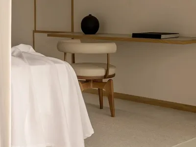 簡約臥室內，白色床鋪擺放於紋理壁紙前，搭配懸浮式書桌與現代椅。