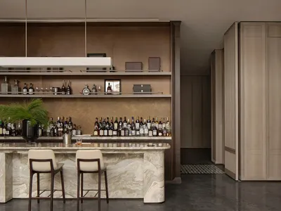 Modern bar with a marble counter featuring a variety of bottles and glasses.