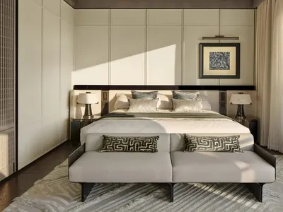 A modern minimalist bedroom with a neutral color palette featuring a large bed, side tables, lamps, and a framed piece of art