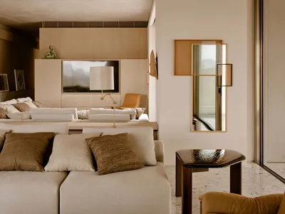 A minimalist living room featuring concrete walls and furniture with earthy tones and textures.