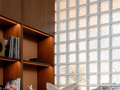 A modern home office featuring a wooden desk, glass block wall, and brick accents