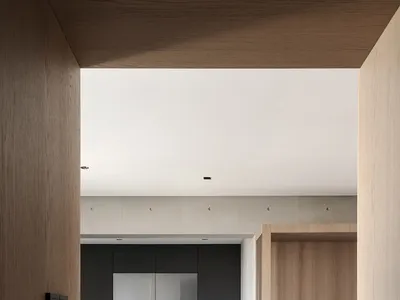 A modern kitchen with minimalist design featuring neutral-toned materials and sleek cabinetry.