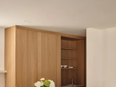 Modern kitchen featuring wooden cabinets and stools with a marble countertop.