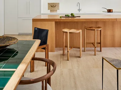 A modern kitchen featuring marble countertops and wooden stools.