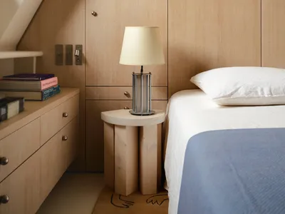 A minimalist bedroom with wooden walls and a bedside table.