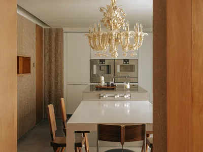 A modern kitchen and dining area featuring a metallic dining table and a crystal chandelier hanging above it.