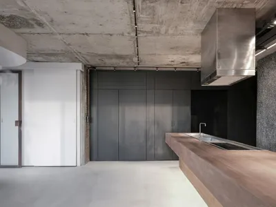 Modern minimalist kitchen featuring concrete, dark wood cabinets, and stainless steel appliances.