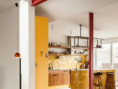 Modern kitchen with vibrant yellow tiles, wooden cabinets, and minimalist design.