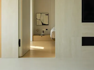 Modern minimalist bedroom with neutral tones, featuring sleek furniture and a minimalist art piece on the wall.