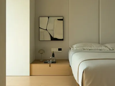 A minimalist bedroom with a white bed and floating nightstand, featuring modern lighting and clean lines.