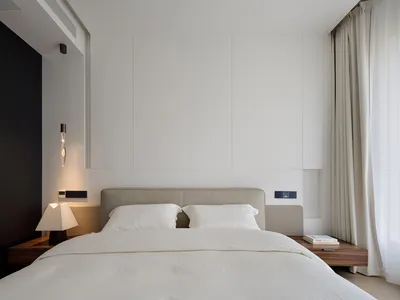 簡約臥室內擺放一張鋪有白色寢具的床，以及一盞懸吊燈具。