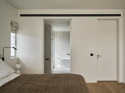 Minimalist bedroom with wooden flooring and a large bed.