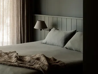 A minimalist bedroom with soft, neutral fabrics and textiles.