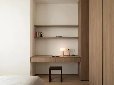 A minimalist bedroom featuring a wooden desk and shelves.