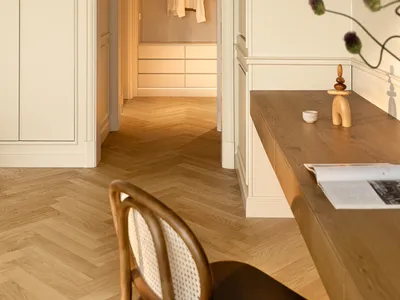 A modern home office with an archway entrance to a closet featuring wooden furniture and architectural molding.