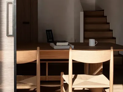 Modern home office featuring wood furniture, books, and a white mug under a pendant light.