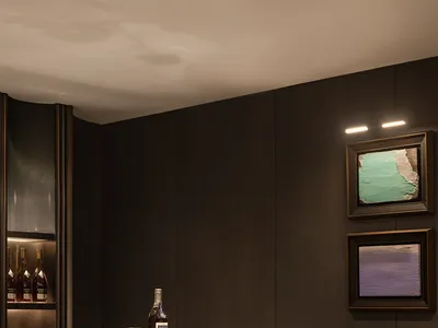 Modern bar with a marble counter, green stools, and framed abstract art in dark interior design space.