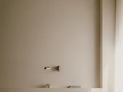 Minimalist bedroom with white canvas walls, wooden furniture, and glass elements.