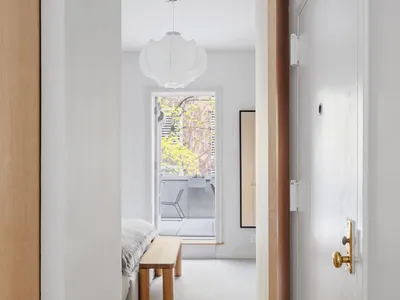 A minimalist bedroom with white walls and wooden furniture.