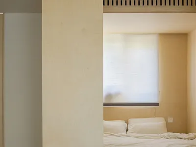 A minimalist bedroom featuring a wooden platform bed and white furniture.