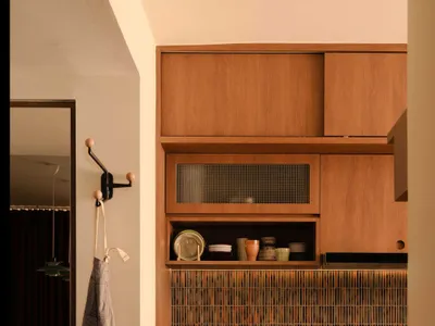 A modern minimalist residential kitchen featuring wooden cabinets and glass mosaic tiles.